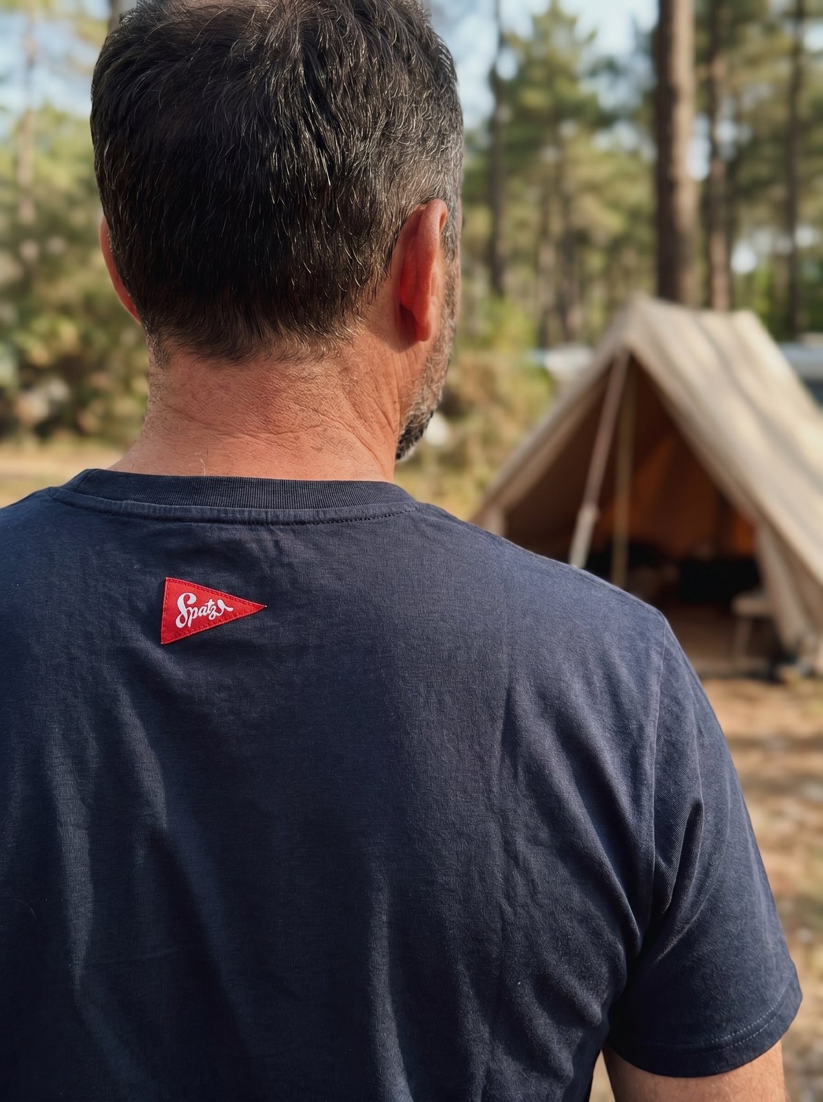 NIKIN Pocket-Shirt navy — Rückansicht mit Spatz-Label im Nacken, Zelt im Hintergrund